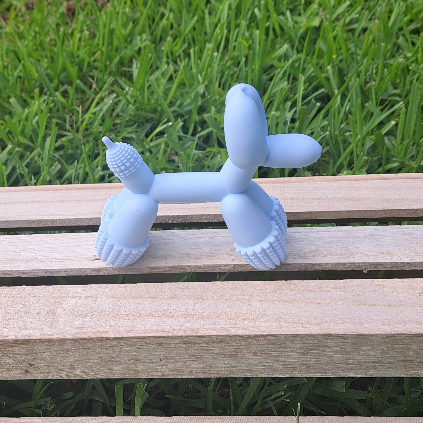 Blue dog toy on a wooden bench with grass in the background