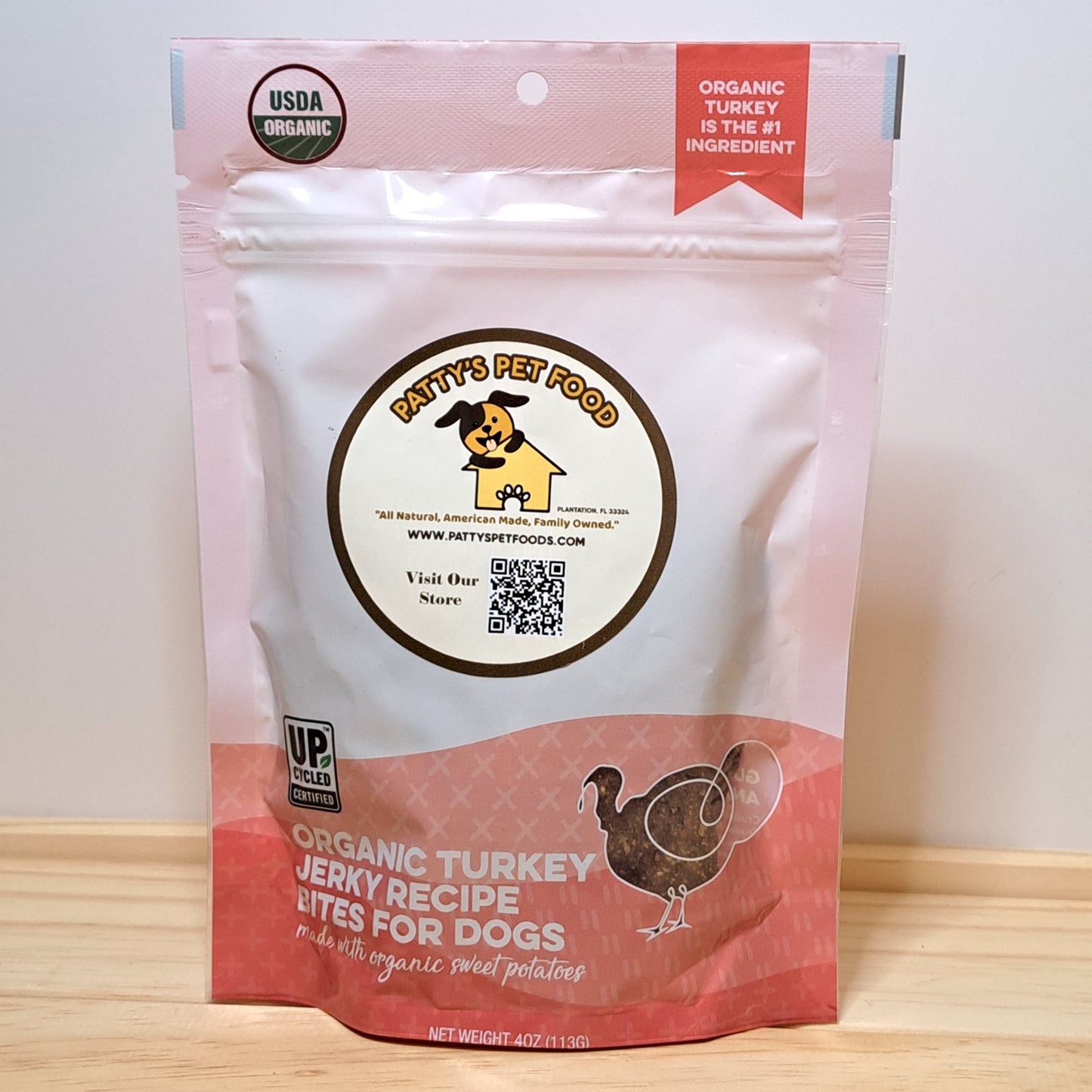 Package of Patty's Pet Food organic turkey jerky recipe for dogs on a wooden surface with a white background