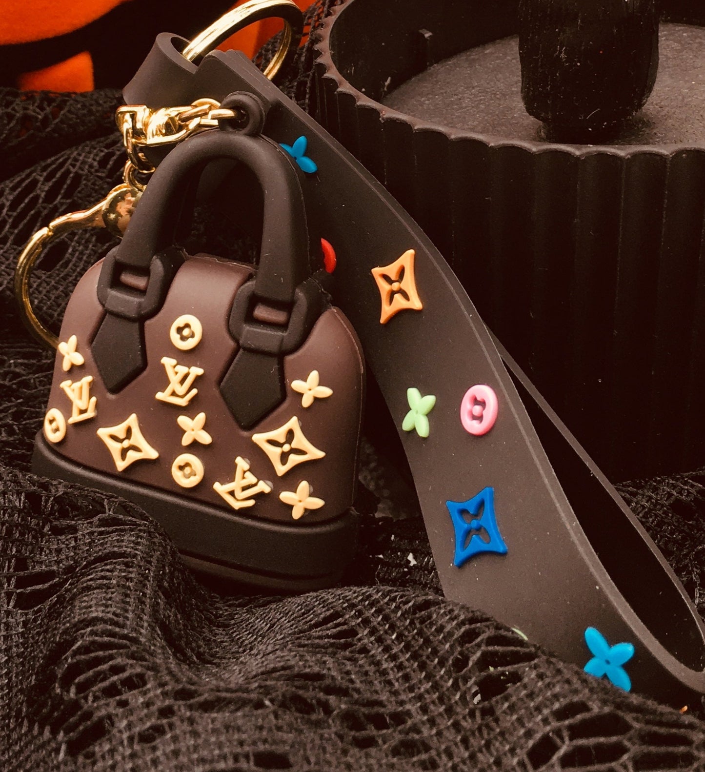 Decorative keychain with colorful studs on a Halloween-themed background with pumpkin and tree.