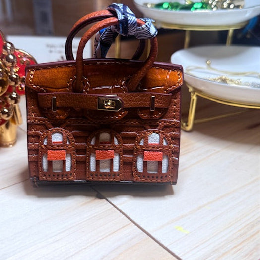 A leather mini purse dog waste bag dispenser in the colors pink, green, and gold, designed to look like a small handbag.