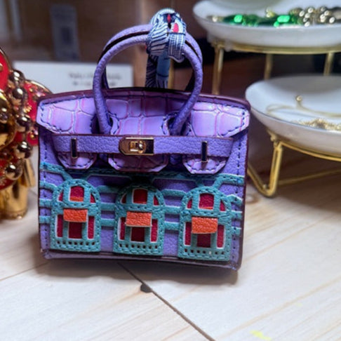 A leather mini purse dog waste bag dispenser in the colors pink, green, and gold, designed to look like a small handbag.