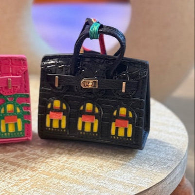 A leather mini purse dog waste bag dispenser in the colors pink, green, and gold, designed to look like a small handbag.