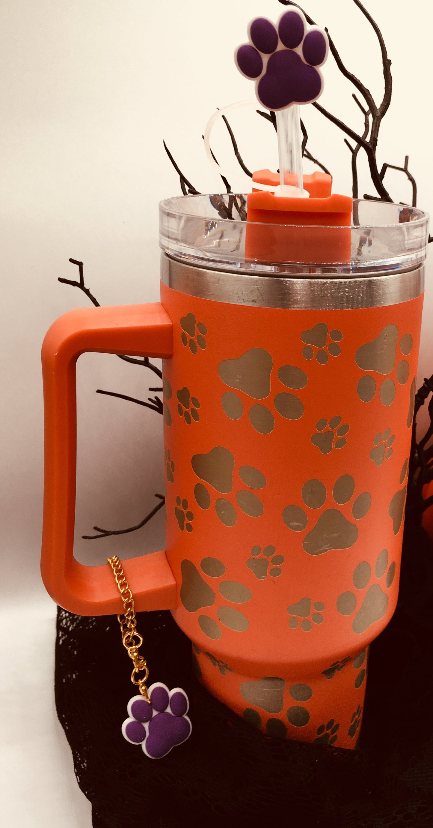 A paw print stanley water bottle with a purple paw print straw cover and purple paw print charm