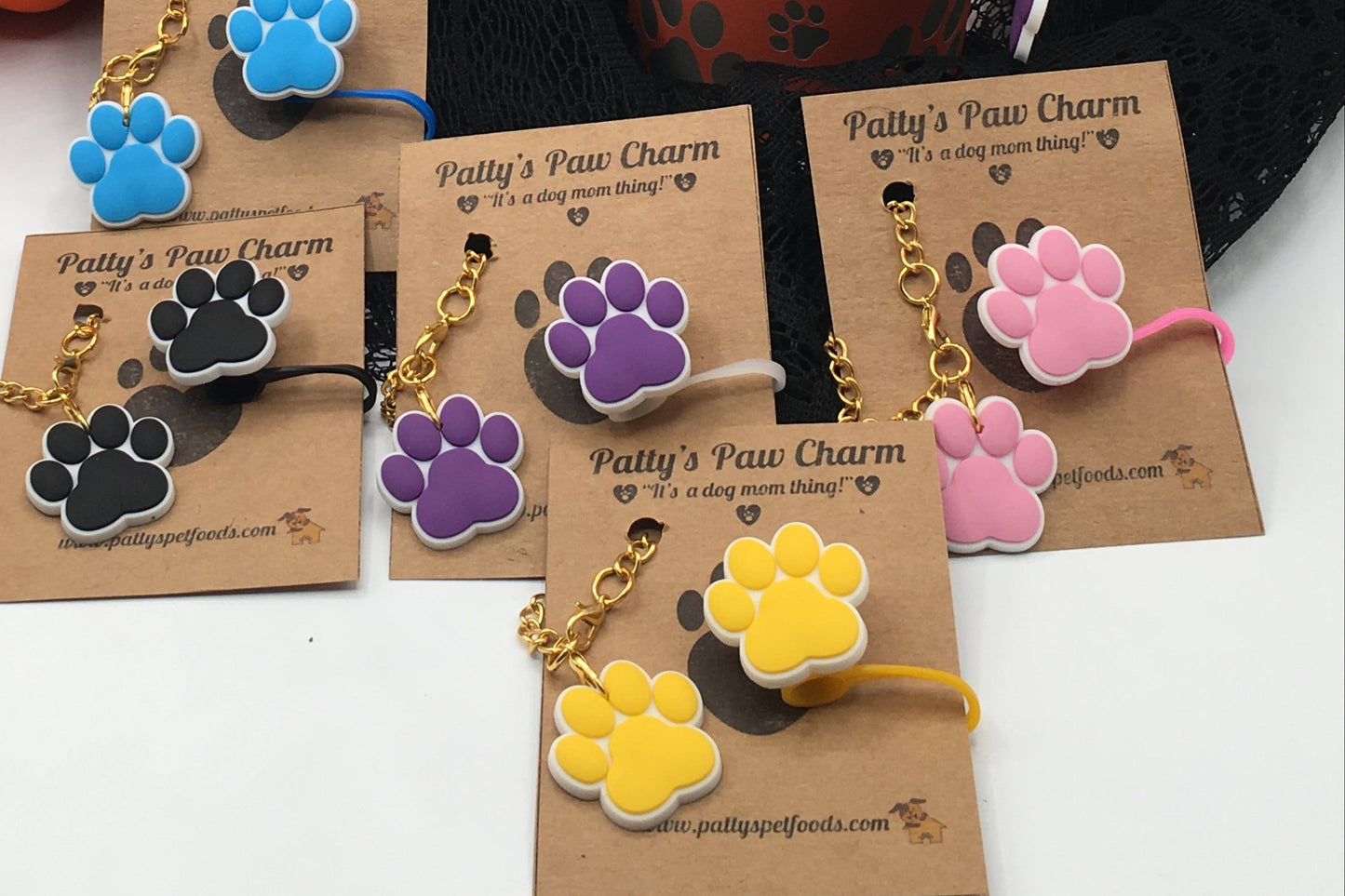 Orange tumbler with paw prints, pumpkin decoration, and paw print earrings on a white background