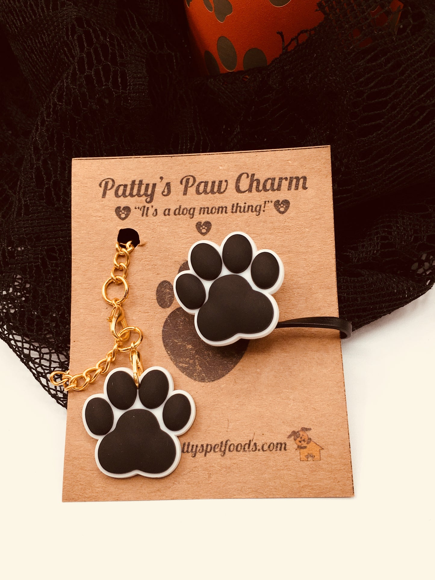 A black silicone water bottle straw cap with a paw print design, displayed along a white background.