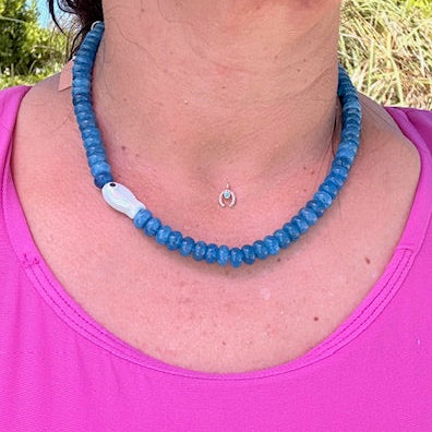 Person wearing a blue beaded necklace and pink top outdoors