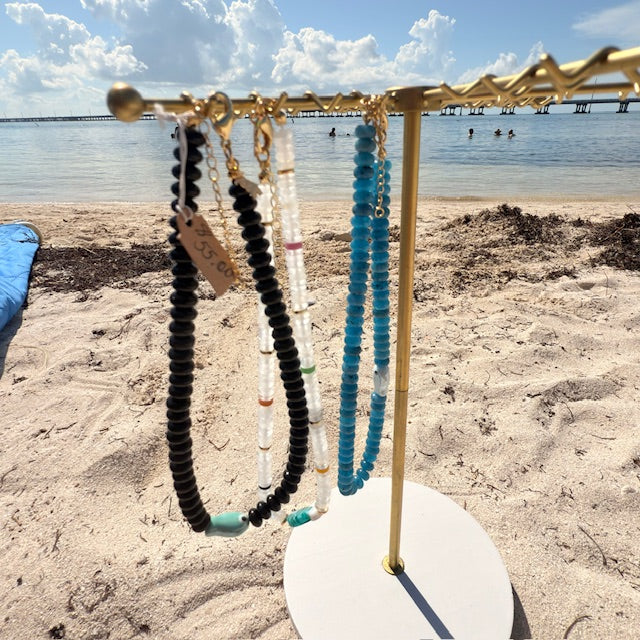 Necklaces on a stand with a beach and water background