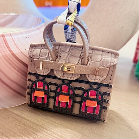 A leather mini purse dog waste bag dispenser in the colors pink, green, and gold, designed to look like a small handbag.
