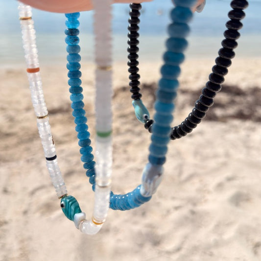Close-up of beaded necklaces with a blurred beach background
